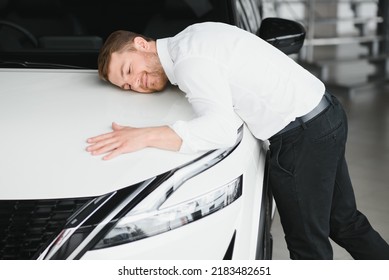 Happy Handsome Bearded Man Buying A Car In Dealership, Guy Hugging Hood Of New Car.