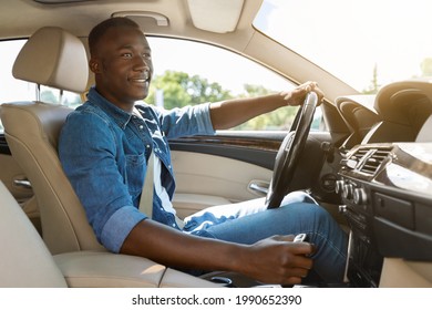 Happy Handsome Black Guy Driving Car, Going To Office Or To Shopping Mall, Side View, Copy Space. Smiling African American Young Man Sitting In Comfortable Auto, Having Car Trip Alone