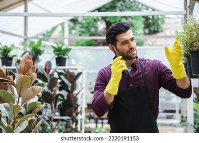 Happy handsome businessman talking on walkie talkie while standing in apron in plants center and porducts order details. Joyful male florist calling on walkie talkie at work. - Powered by Shutterstock