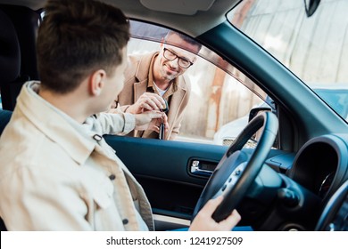 Happy Handsome Father Giving Car Key To Teen Son On Street