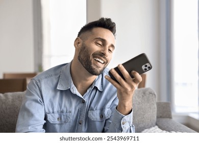 Happy handsome Hispanic man using voice assistant on mobile phone, leaving message, talking on cellphone, smiling, laughing, enjoying wireless Internet technology, communication - Powered by Shutterstock