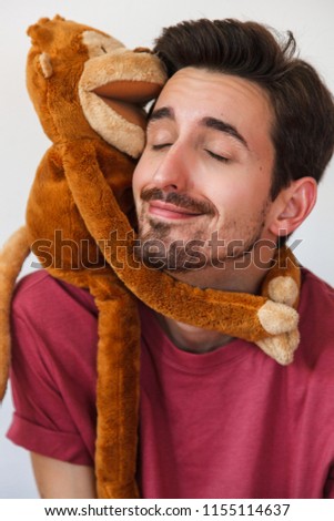 Happy and handsome Man with beard playing with stuffed animal. Monkey stuffed. Kid Stuff
