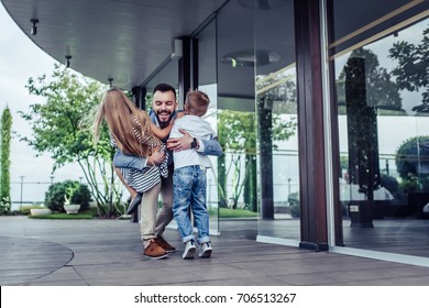 Happy handsome man with children on hands. Dad is arriving home from work. Little charming daughter and son are meeting him. Family is having fun in park. - Powered by Shutterstock