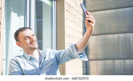 Happy Handsome Man Having A Facetime Video Call Talking To His Family. Smiling Man Taking Smelfies Outside On A Sunny Day. Self Isolation At Home On Balcony. 