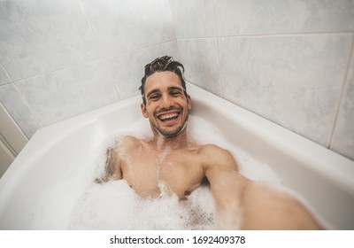 Happy handsome man take a selfie inside bathtub in the bathroom of the hotel on holiday.