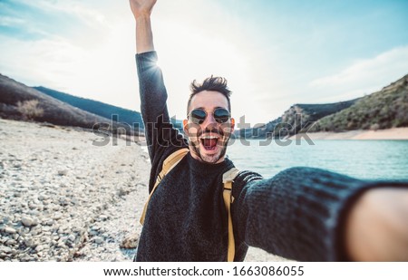 Happy handsome man takes a selfie portrait at vacation outdoor. Travel backpacker concept