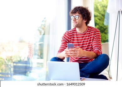 Happy handsome man text messaging and usin laptop while relaxing at home.  - Shutterstock ID 1649012509