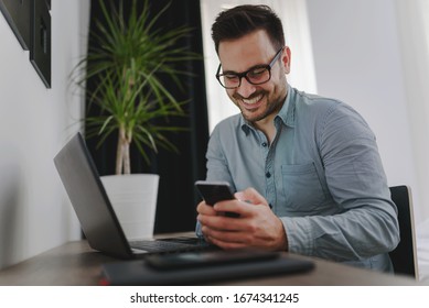 Happy Handsome Man Texting On Smartphone At Work