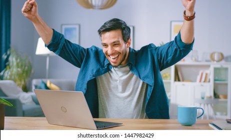 Happy Handsome Man Working on a Laptop Celebrates Successful Endeavor with YES Gesture. Freelances Working from His Living Room Has Stroke of Luck and Wins Big.