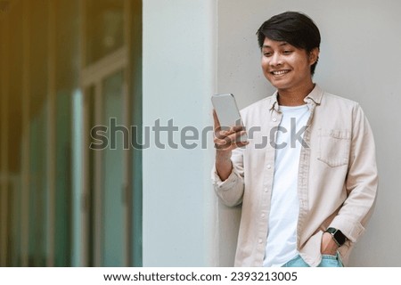 Happy handsome young asian guy in casual IT professional going to office, walk by street, using phone, checking email, using business mobile app, smiling, copy space for advertisement