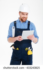 Happy Handsome Young Builder In Helmet Standing And Using Tablet