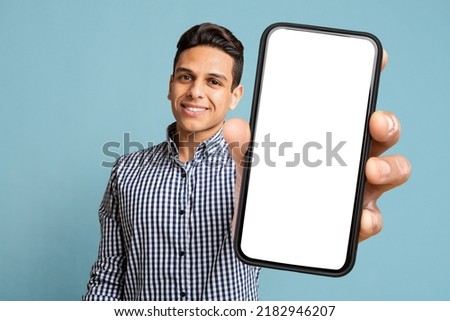 Happy Handsome Young Latino Man Showing Modern Cell Phone With White Empty Screen And Smiling On Blue Studio Background, Recommending Dating App. Free Space And Mockup For Advertisement, Collage