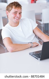 Happy Handsome Young Male College Student  Using His Computer In The Campus Common Area/high School Study Room (shallow DOF, Color Toned Image)