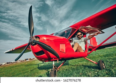 Happy Handsome Young Man Pilot Sitting In Cabin Of Small Plane. Low Angle