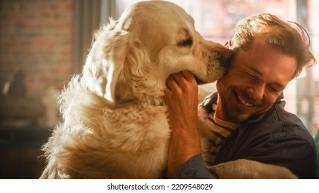 Happy Handsome Young Man Play With Dog At Home, Gorgeous Golden Retriever. Attractive Man Sitting On A Floor. Excited Dog Licking The Owner That Teases The Pet. Having Fun In The Stylish Apartment.