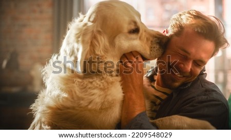 Happy Handsome Young Man Play with Dog at Home, Gorgeous Golden Retriever. Attractive Man Sitting on a Floor. Excited Dog Licking the Owner that Teases the Pet. Having Fun in the Stylish Apartment.