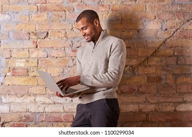A happy handsome young man using a laptop in a sweater.