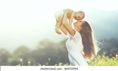 happy harmonious family outdoors. mother throws baby up, laughing and playing in the summer on the nature - Shutterstock ID 444753994