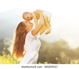 happy harmonious family outdoors. mother throws baby up, laughing and playing in the summer on the nature