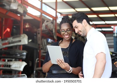 Happy Harmony people at workplace, smiling white man and African American working together, checking product stock at auto spare parts store warehouse with many engine parts as blurred background