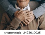 Happy healthcare worker hugging a senior man at home and support encouraging old people. A happy patient is holding the caregiver for a hand while spending time together. Elderly health care concept.