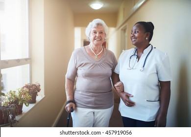 Happy healthcare worker and senior woman together at nursing home. Caring female doctor assisting a senior patient to walk. - Shutterstock ID 457919056