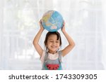 Happy and healthy asian little girl is raising the globe model with love and concept of preserve, save and protect the earth from environment problem and global warming, kid education at home.