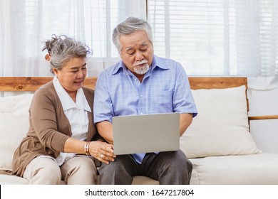 Happy healthy Asian senior elderly couple web chat on computer at home. Retired man and woman enjoy shopping or streaming online via website by using laptop. Elder retirement activity and lifestyle - Powered by Shutterstock