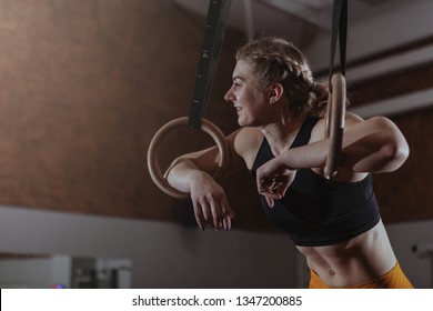 Happy healthy athletic woman laughing, looking away, resting after gymnastic rings workout. Cheerful crossfit female athlete relaxing at the gym, after exercising - Powered by Shutterstock