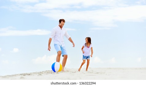 Happy Healthy Family Father And Daughter Running On The Beach With Ball Having Fun Together