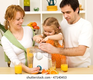 Happy Healthy Family With A Kid Making Fresh Fruit Juice In The Kitchen