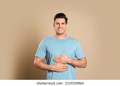 Happy Healthy Man Touching His Belly On Beige Background