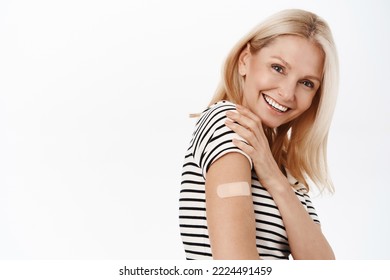 Happy And Healthy Mature Woman, 50 Years Old, Has Band Aid On Shoulder, Smiling And Laughing, Standing In Tshirt Over White Background.