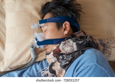 Happy and healthy senior man wearing cpap mask sleeping smoothly without snoring on his side open arm.Obstructive sleep apnea therapy,close up  top view.
