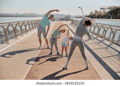 Happy Healthy And Sporty Family Are Doing Workout Trainings In Sunny Day