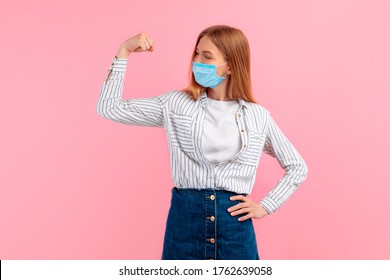 Happy Healthy Strong Young Woman In A Medical Protective Mask On Her Face, Showing Biceps On Her Arm, On An Pink Background