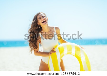 happy healthy woman in white swimwear on the ocean coast holding yellow inflatable lifebuoy. protect your hair from sun, heat, and humidity before heading to the beach. Sun protected hair.