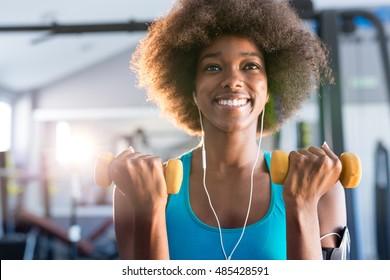 Gute, junge Afroamerikanerin in einem Fitnessraum mit einem Paar Hanbells