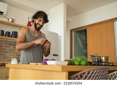 Happy And Healthy Young Man Meal Prepping Whole Vegetarian Meal In The Kitchen. High Quality Photo. Feel Good, Healthy And Health Concept. 