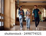 Happy high school friends communicating after a class in hallway. Copy space.