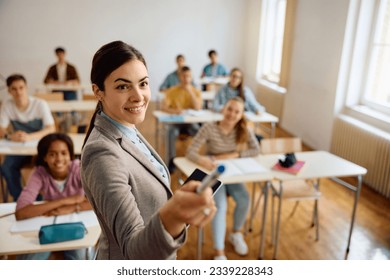 Happy high school professor teaching her students during a class in the classroom. - Shutterstock ID 2339228343
