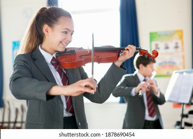 Happy High School Student Playing Violin During A Music Class.