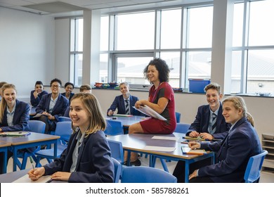 Happy High School Students And A Teaching Assistant Are Laughing At Their Teacher Who Is Out Of The Frame, During A School Lesson.