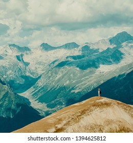 A happy hiker with a backpack stands on a cliff of huge mountains. She looks into the distance. Picturesque landscape with clouds. Wallpaper for your montage-aim, top, business, concept thinking. - Powered by Shutterstock