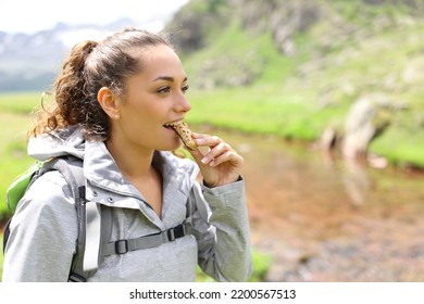 Happy hiker eating a cereal bar walking in the mountain - Shutterstock ID 2200567513