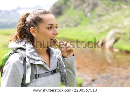 Happy hiker eating a cereal bar walking in the mountain
