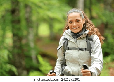 Happy hiker trekking looking at you in a forest - Powered by Shutterstock