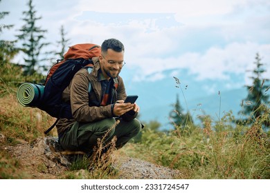 Happy hiker using mobile phone while relaxing in nature. Copy space. - Powered by Shutterstock