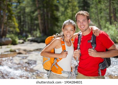 Happy hikers couple hiking in summer forest camping with backpacks. Two friends, Asian woman, Caucasian man smiling portrait, interracial group. - Powered by Shutterstock