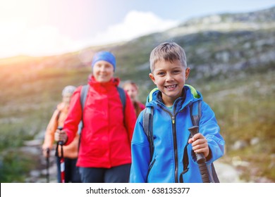 Happy Hiking Boy With Trekking Sticks In The Mountains With His Family. Norway